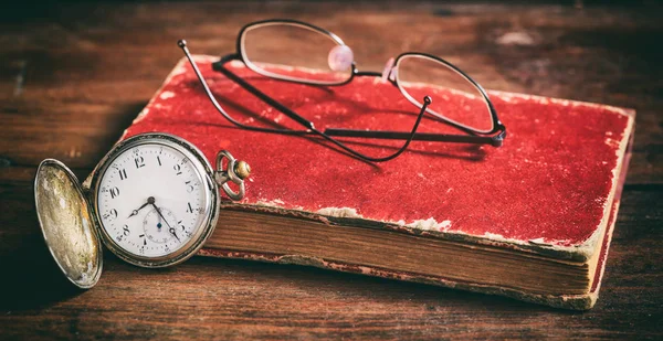 Карманные часы и очки на старой книге — стоковое фото