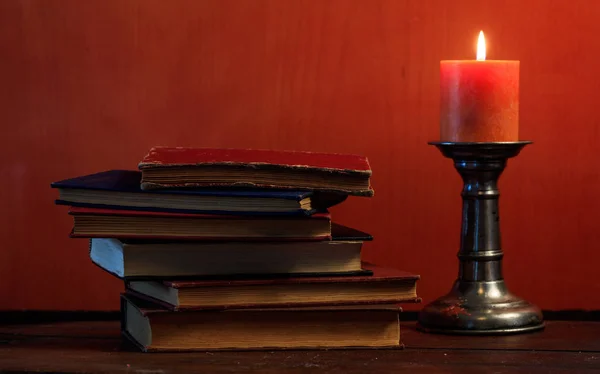 Vintage books and candle on blackboard background — Stock Photo, Image