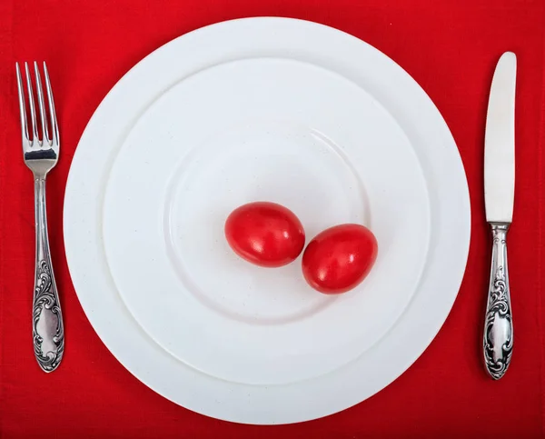 Ovos de Páscoa em uma chapa na toalha de mesa vermelha — Fotografia de Stock