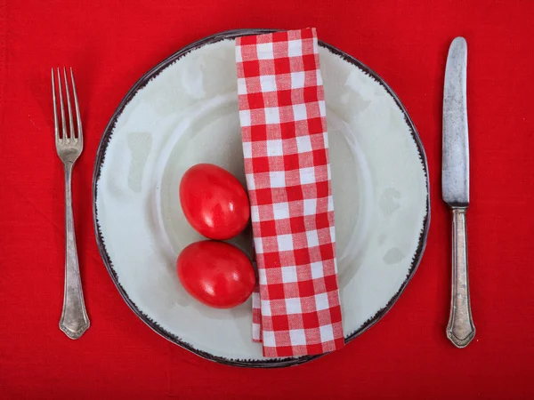 Ovos de Páscoa em uma chapa na toalha de mesa vermelha — Fotografia de Stock