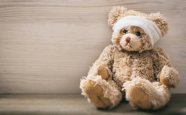 Teddybeer met pleister op een houten vloer — Stockfoto