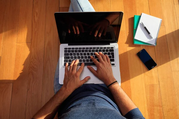 Arbetsytan hemma. Studenten arbetar med en laptop på golvet. — Stockfoto