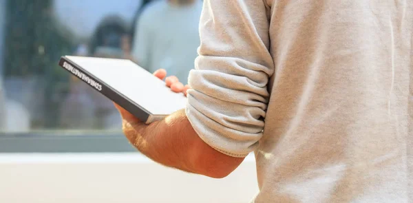 Mann hält ein Buch vor einem Glasfenster — Stockfoto