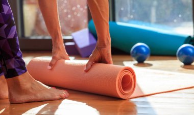 Kadın bir yoga mat ahşap zemin üzerinde haddeleme