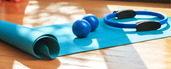 Yoga mat and exercise weights on wooden floor