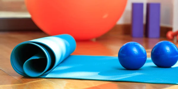 Yoga mat and exercise weights on wooden floor Royalty Free Stock Photos