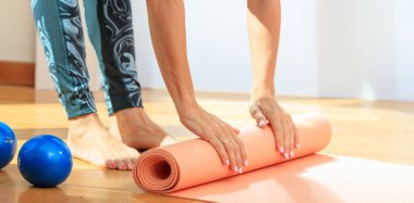 Kadın bir yoga mat ahşap zemin üzerinde haddeleme