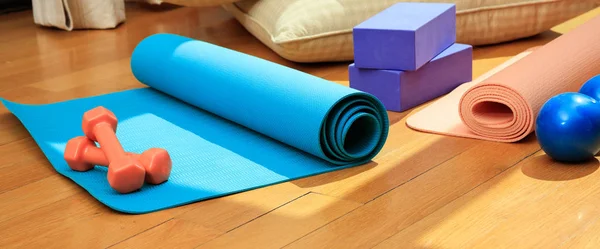 Tapete de ioga e pesos de exercício no chão de madeira — Fotografia de Stock