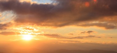 Güzel gün batımı gökyüzü üzerinde. Altın güneş Dağların üzerinden bulutlar aydınlatır. Sol taraftaki güneşin olduğunu.