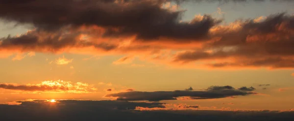 Hermosa puesta de sol en el cielo. El sol dorado ilumina las nubes. El sol está en el lado izquierdo . — Foto de Stock