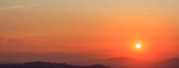 Hermosa puesta de sol en el cielo sobre el fondo de montañas. El sol está en el lado derecho . — Foto de Stock