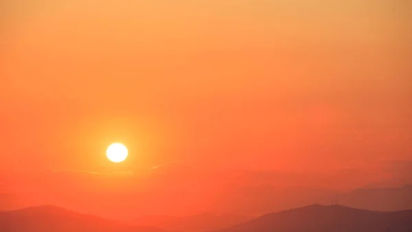 Hermosa puesta de sol en el cielo sobre el fondo de montañas. El sol está en el lado izquierdo . —  Fotos de Stock