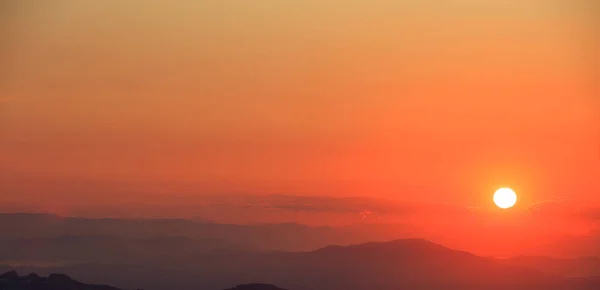 Hermosa puesta de sol en el cielo sobre el fondo de montañas. El sol está en el lado derecho . —  Fotos de Stock