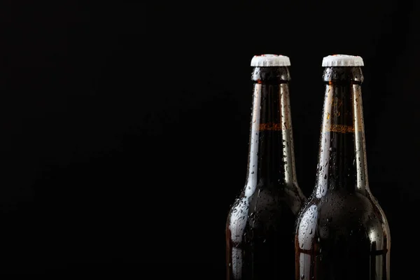 Primer plano de dos botellas de cerveza aisladas sobre fondo negro —  Fotos de Stock