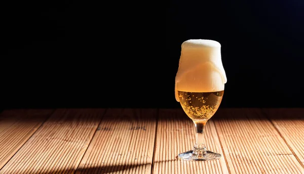 Un bicchiere di birra su un tavolo di legno, sfondo scuro — Foto Stock