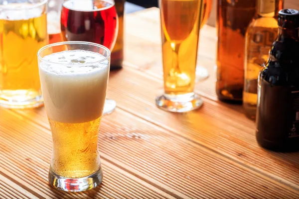 Um balcão de pub de madeira, concentre-se em um copo gelado cheio de cerveja — Fotografia de Stock