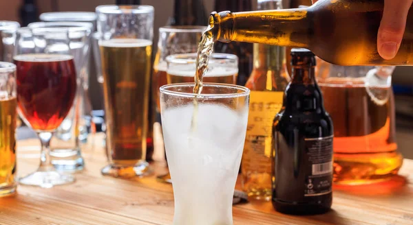 Derramando cerveja em um copo gelado vazio de cerveja em um fundo de pub — Fotografia de Stock