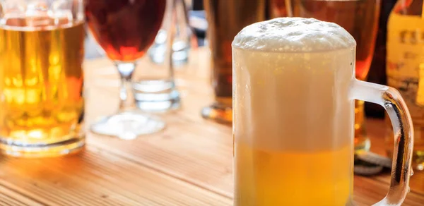 Um balcão de pub de madeira, concentre-se em uma caneca gelada cheia de cerveja — Fotografia de Stock
