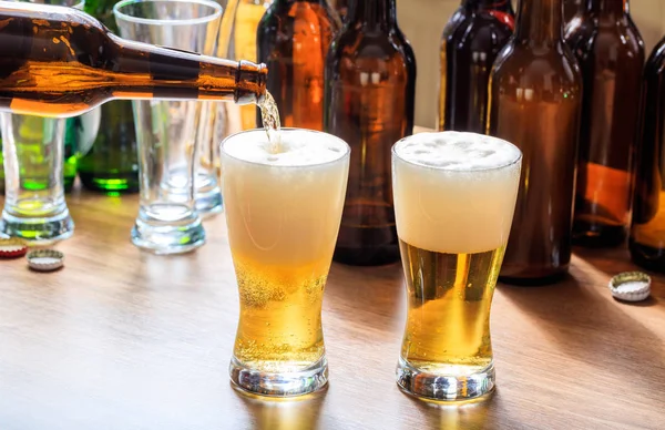 Derramando cerveja em um copo de cerveja em um fundo de pub — Fotografia de Stock