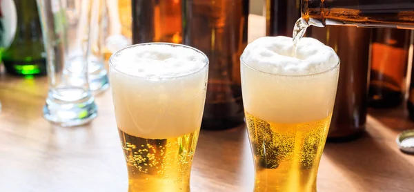Derramando cerveja em um copo de cerveja em um fundo de pub — Fotografia de Stock