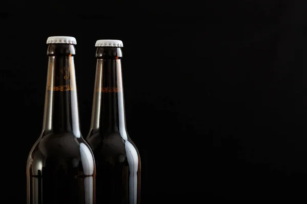 Primo piano di due bottiglie di birra isolate su sfondo nero — Foto Stock
