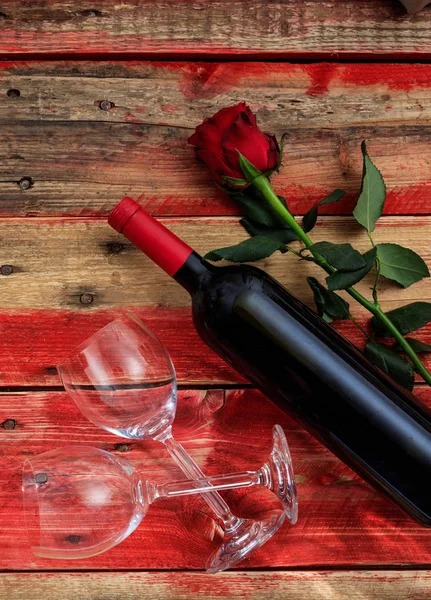 Dia dos Namorados. Garrafa de vinho tinto, copos e uma rosa no fundo de madeira vermelho — Fotografia de Stock