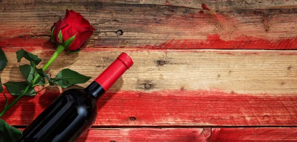 Valentines day. Red wine bottle and red rose on wooden background — Stock Photo, Image