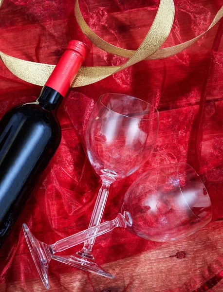 San Valentino. Bottiglia di vino rosso e bicchieri su tessuto rosso — Foto Stock