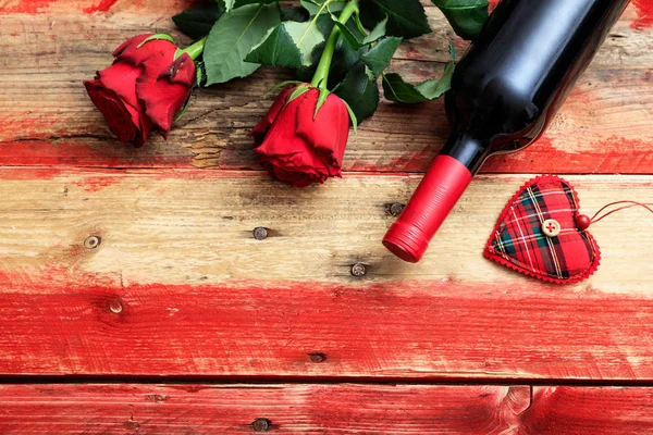 Valentines day. Red wine bottle and red roses on wooden background — Stock Photo, Image