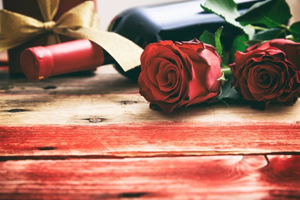 De dag van Valentijnskaarten. Fles met rode wijn, rozen en een gift op houten achtergrond — Stockfoto