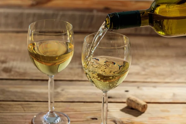 Наливание белого вина в стакан на деревянном фоне — стоковое фото