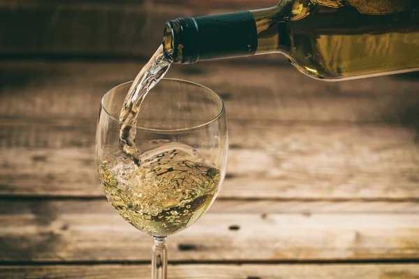 Despejando vinho branco em um copo no fundo de madeira — Fotografia de Stock