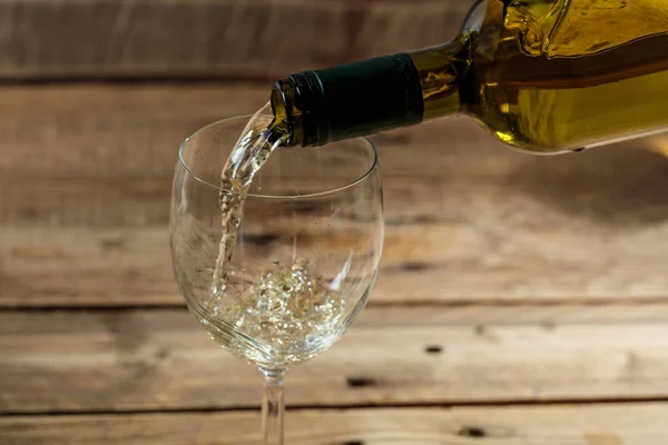 Despejando vinho branco em um copo no fundo de madeira — Fotografia de Stock