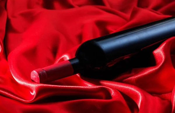Ημέρα του Αγίου Βαλεντίνου. Μπουκάλι κόκκινο κρασί στο κόκκινο σατέν — Φωτογραφία Αρχείου