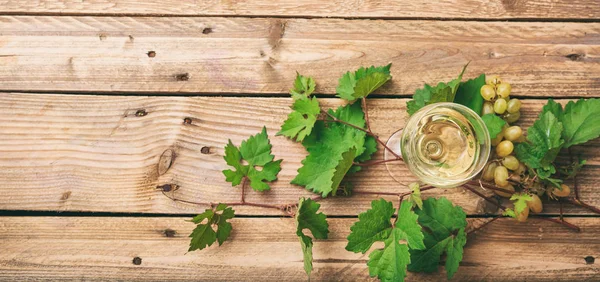 Sklenka na bílé víno a čerstvých hroznů na dřevěné pozadí, kopírování prostor — Stock fotografie