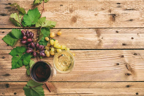 Copos de vinho tinto e branco e uvas frescas em fundo de madeira, espaço de cópia — Fotografia de Stock