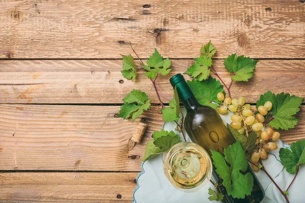 Copo de vinho branco e garrafa e uvas frescas em fundo de madeira, espaço de cópia — Fotografia de Stock