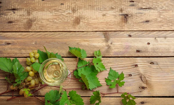 Copo de vinho branco e uvas frescas em fundo de madeira, espaço de cópia — Fotografia de Stock