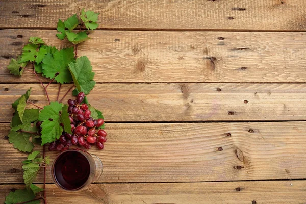 Copo de vinho tinto e uvas frescas em fundo de madeira, espaço de cópia — Fotografia de Stock