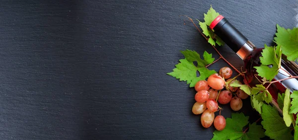 Botella de vino rosa y uvas frescas sobre fondo negro, espacio para copiar —  Fotos de Stock