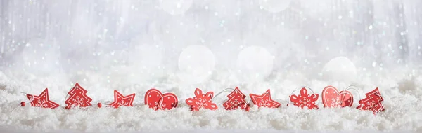 Rote Weihnachtsschmuck Reihe auf Weihnachten schneebedeckten Bokeh Hintergrund — Stockfoto