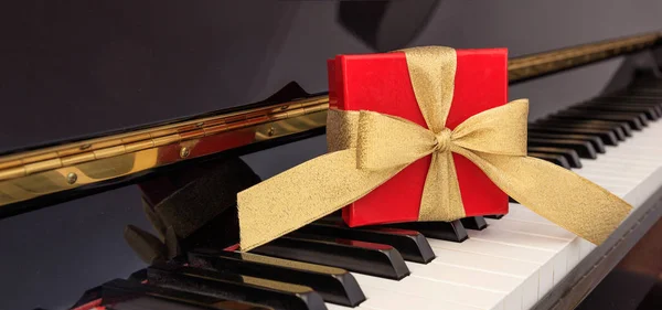 Red gift box on piano keyboard — Stock Photo, Image