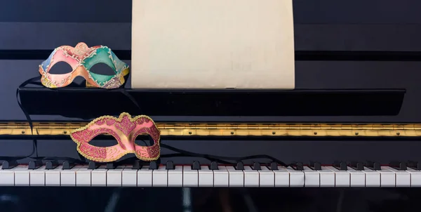 Maschere di Carnevale sulla tastiera del pianoforte, vista frontale — Foto Stock