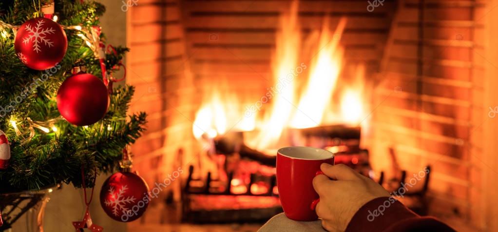 Taza de café sobre fondo de chimenea ardiente y árbol de Navidad