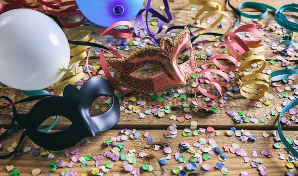 Carnival party. Masks, confetti and serpentines on wooden floor