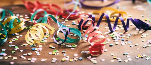 Kleurrijke confetti en serpentines op houten achtergrond — Stockfoto