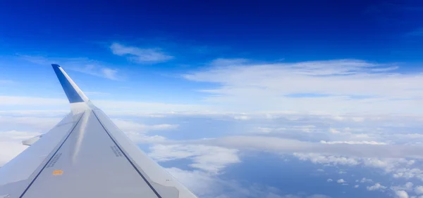 Witte wolken op een blauwe hemel uit een vliegtuig venster achtergrond. Ruimte voor tekst. — Stockfoto