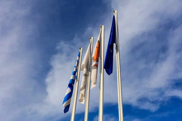 Cypern, Grekland, Eu och Larnaka kommun flaggor på stolpar. Molnig himmel bakgrund. — Stockfoto