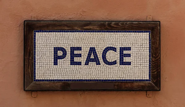 Wort Frieden aus Würfeln. Mosaikmuster, Holzrahmen, warmer brauner Hintergrund. Nahsicht. — Stockfoto