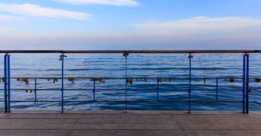 Paslı kilit aşk kanıtlayan soyulmuş korkuluk kapalı. Görünümü, mavi gökyüzü ve deniz arka plan kadar yakın.